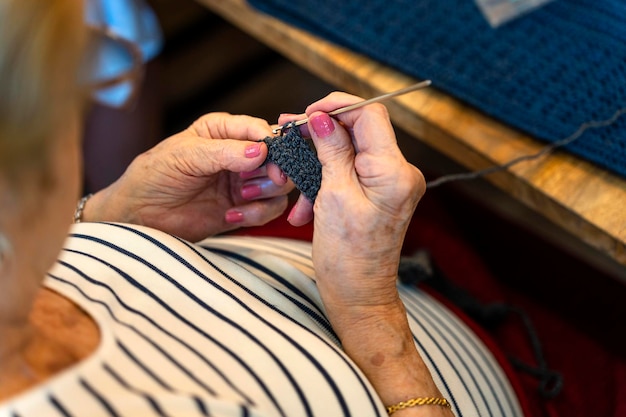 Crochet Club Close-up van een oudere vrouw die aan het breien is