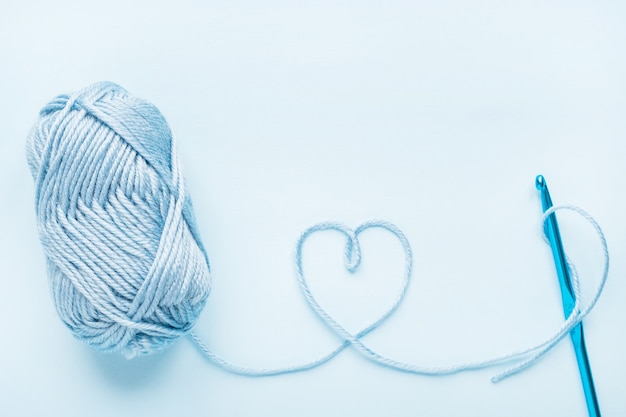 Crochet heart, hook and ball of yarn on a blue background