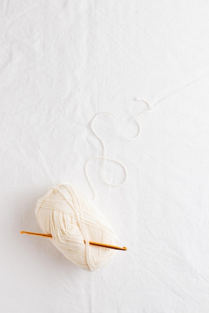 Photo crochet hook and ball of cotton yarn white color on a white table