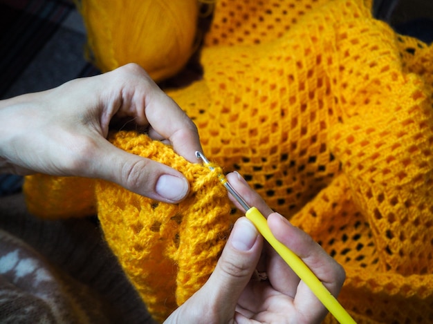 Crochet. Woman crochet yellow yarn. Close-up of the hands.