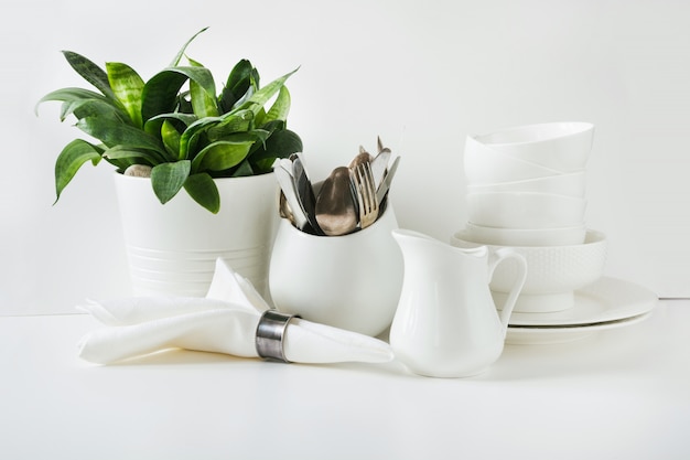 Crockery,dish, utensils and other different white stuff on white table-top. 