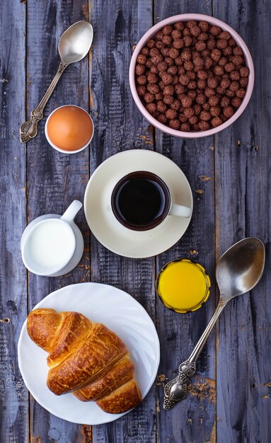 Croissant, cereal flake, coffee, milk, orange juice, boiled egg for breakfast