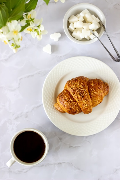A croissant and coffee on a marble surface 