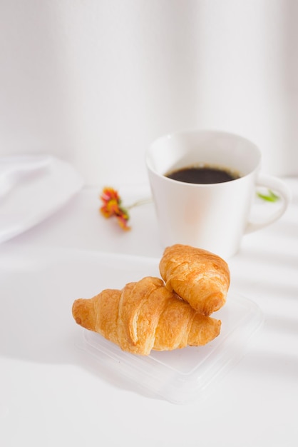 Foto croissant e tazza di caffè nella luce del mattino