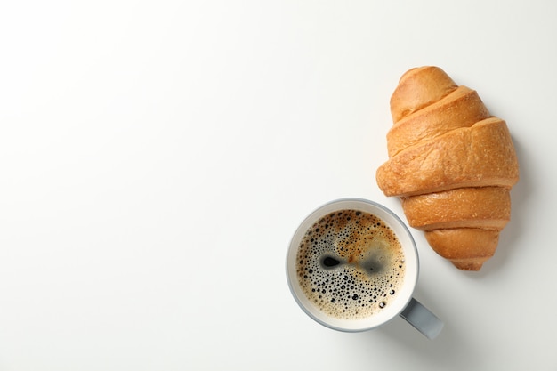 Croissant e tazza di caffè su fondo bianco, vista superiore