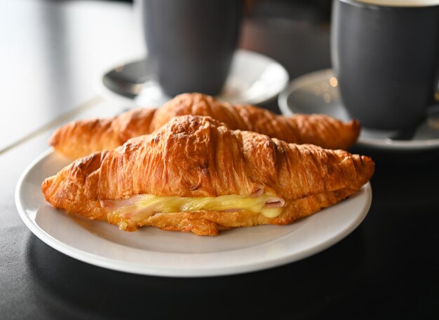 写真 クロワッサン・ハム・チーズ (croissant ham cheese) は,フランス料理のクロワッサンで,ホワイトプレートにハムとチーズとコーヒーを入れる.