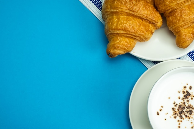 Foto croissant e latte caldo sul blu
