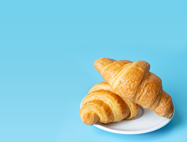 Croissant in een witte plaat op kleurenachtergrond