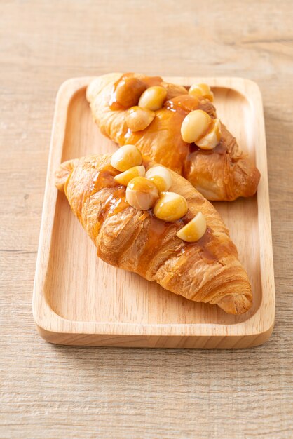 croissant met macadamia en karamel op houten plaat