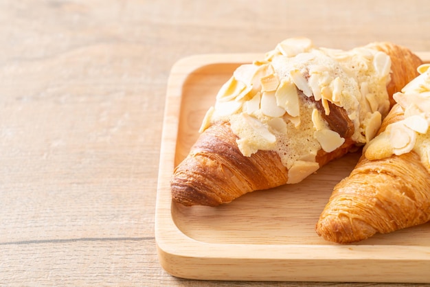 croissant met room en amandelen op houten plaat