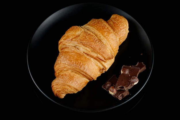 Foto croissant met stukjes chocolade op een zwarte plaat bovenaanzicht