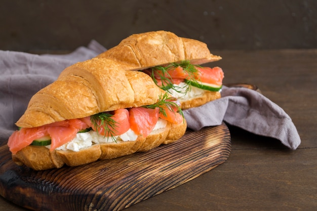 Croissant met zalm en roomkaas op een houten bord.