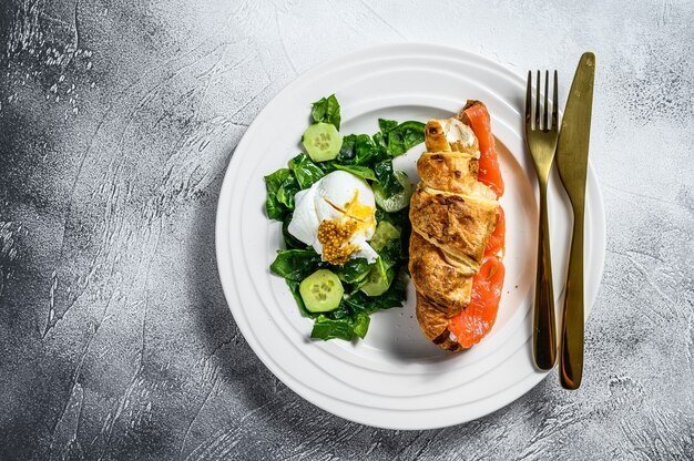 Croissant met zalm geserveerd met verse spinazie en ei