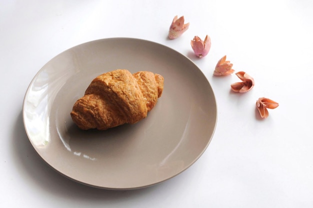 Croissant op het bord met versierde bloemen boven het zicht