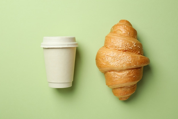 Croissant and paper cup on green