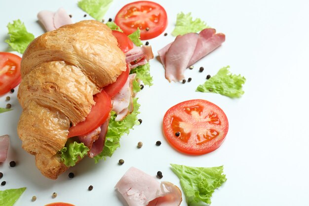 Croissant sandwich en ingrediënten op wit, close-up