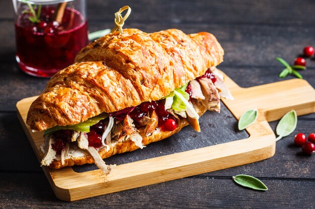 Croissant sandwich with duck meat, cream cheese and cranberry sauce on the board
