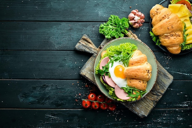 Сэндвич с круассаном с жареным яйцом и колбасой, помидорами и луком Вид сверху Свободное место для текста