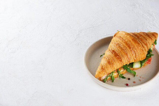 Croissant sandwich with salmon cream cheese and arugula in a plate