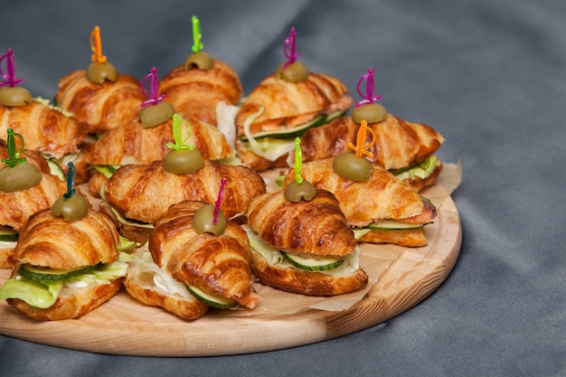 Croissant sandwich with salmon, lettuce and cucumbers. Croissants with red fish on a wooden cutting board.