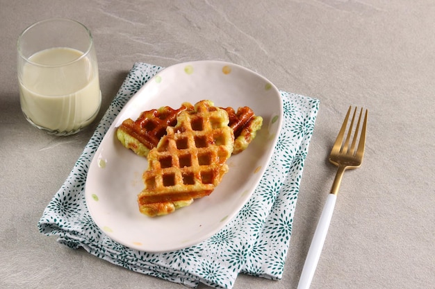 Croissant Wafel of Croffle met een glas matcha melk geserveerd in de ovale plaat met vork.