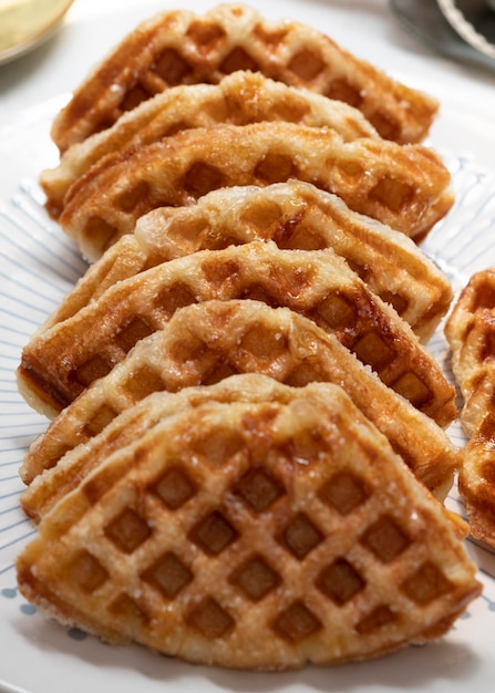 Croissant waffle or its famous names croffle on white plate\
with white background.