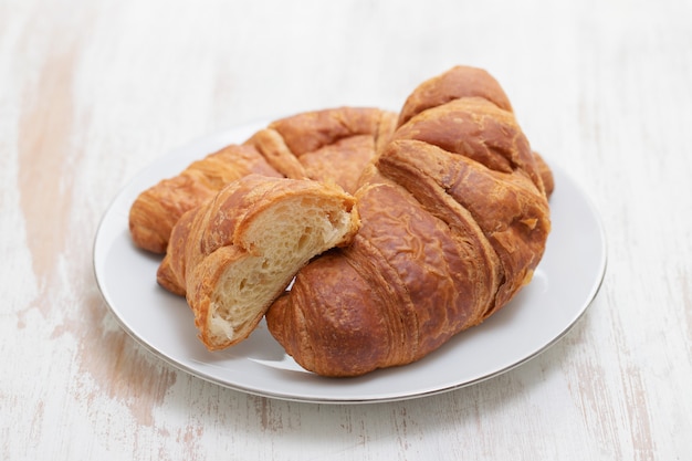 Croissant on white dish on white wooden surface