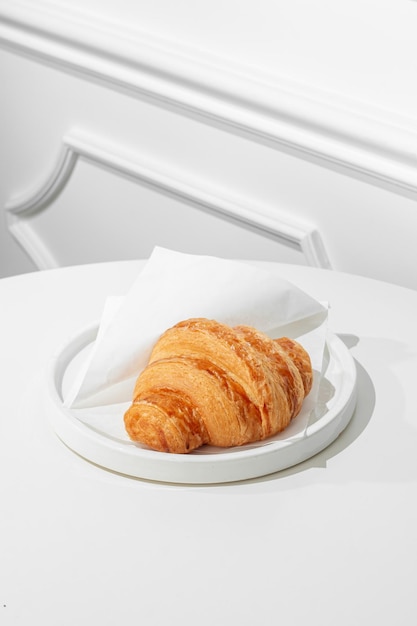 Photo croissant on a white table sunny hard light