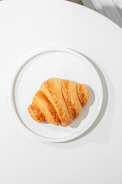 Photo croissant on a white table sunny hard light