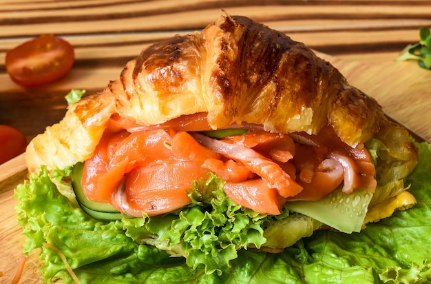 croissant wish smoked salmon fillet and vegetables on wooden table close up side view