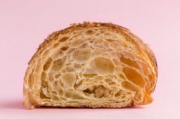 Photo croissant with almonds on pink background