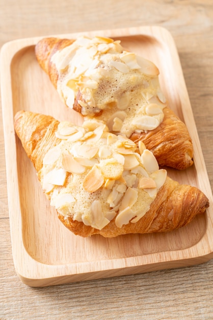 croissant with cream and almonds on wood plate