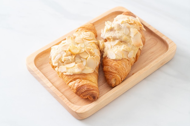 croissant with cream and almonds on wood plate