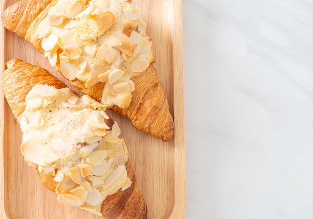 croissant with cream and almonds on wood plate