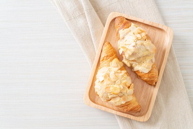 croissant with cream and almonds on wood plate