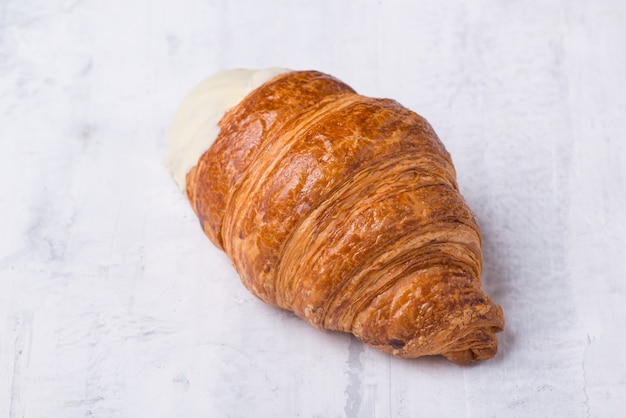 Croissant with cream filling on a light background