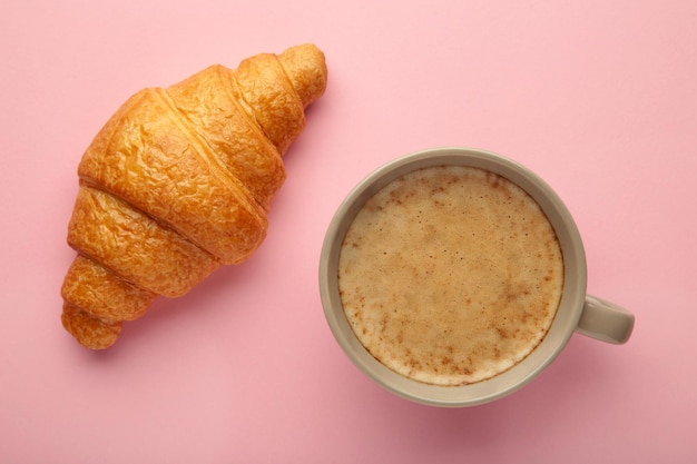 Croissant with cup of coffee on pink background High quality photo