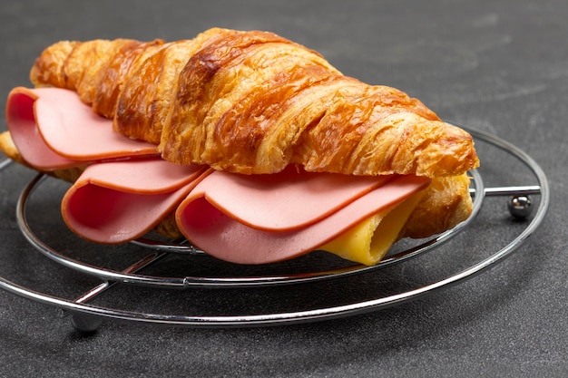 Croissant with ham and cheese. Closeup. Black background.