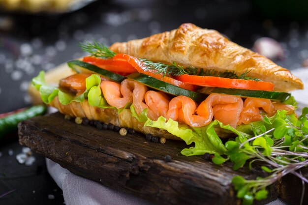 croissant with ham and greens on a wooden cutting kitchen board, with vegetables, cherry tomatoes