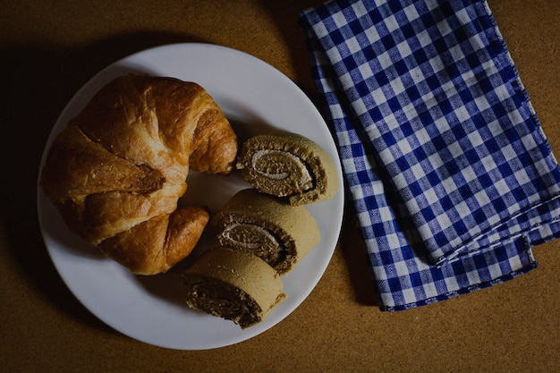 Croissant with jam roll on white plate