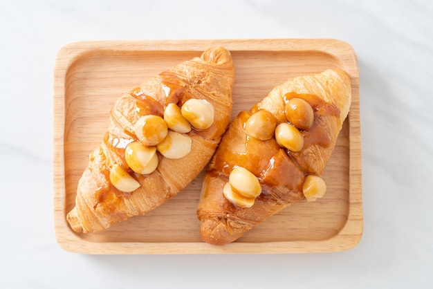 Croissant con macadamia e caramello su piatto di legno