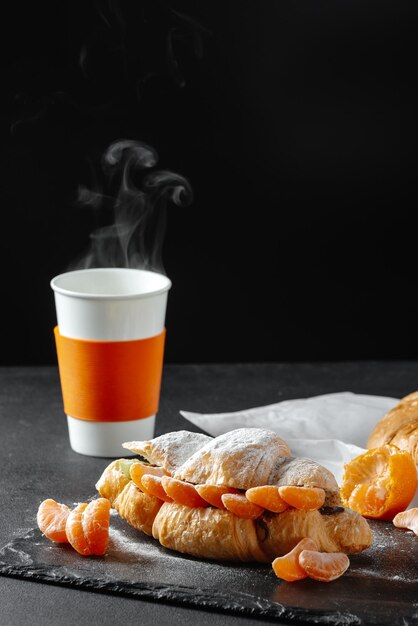 Croissant with mandarins sweet on a dark background homemade croissants falling powdered sugar verti