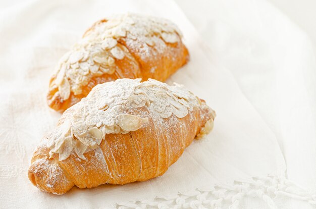 croissant with powdered sugar and almond flakes on white background