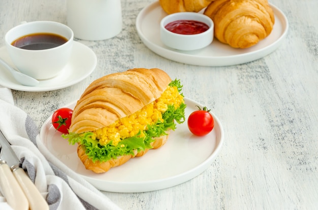 Croissant with scrambled eggs, lettuce and cherry tomatoes