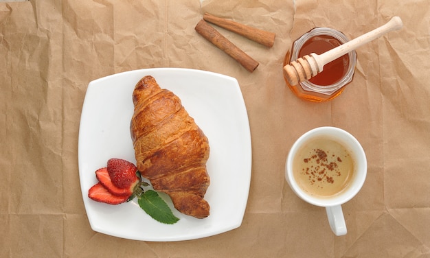 Photo croissant with strawberry, honey and cinnamon tea