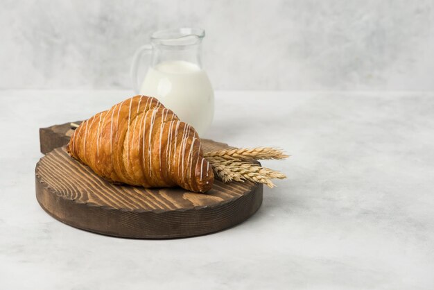 Foto croissant sul piatto di legno con fondo bianco della composizione del latte per la prima colazione