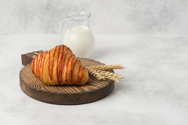 Foto croissant sul piatto di legno con fondo bianco della composizione del latte per la prima colazione