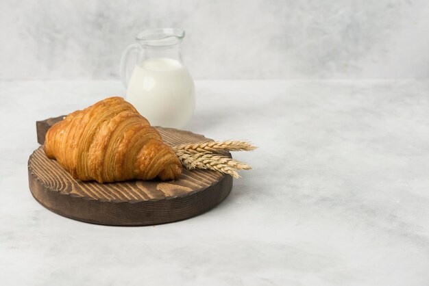 Foto croissant sul piatto di legno con fondo bianco della composizione del latte per la prima colazione