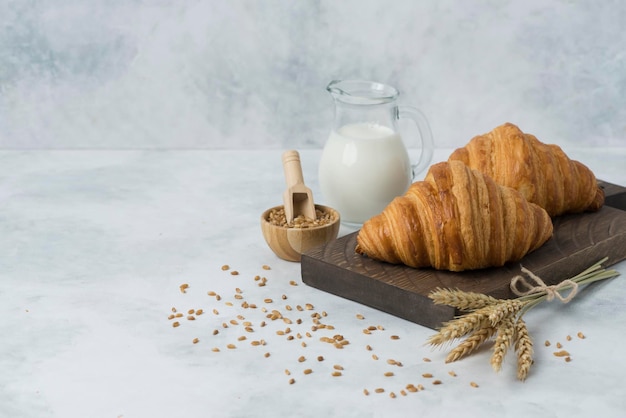 Croissant sul piatto di legno con fondo bianco della composizione del latte per la prima colazione