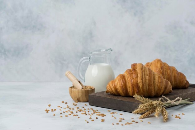 Photo croissant on wood plate with milk composition white background for breakfast